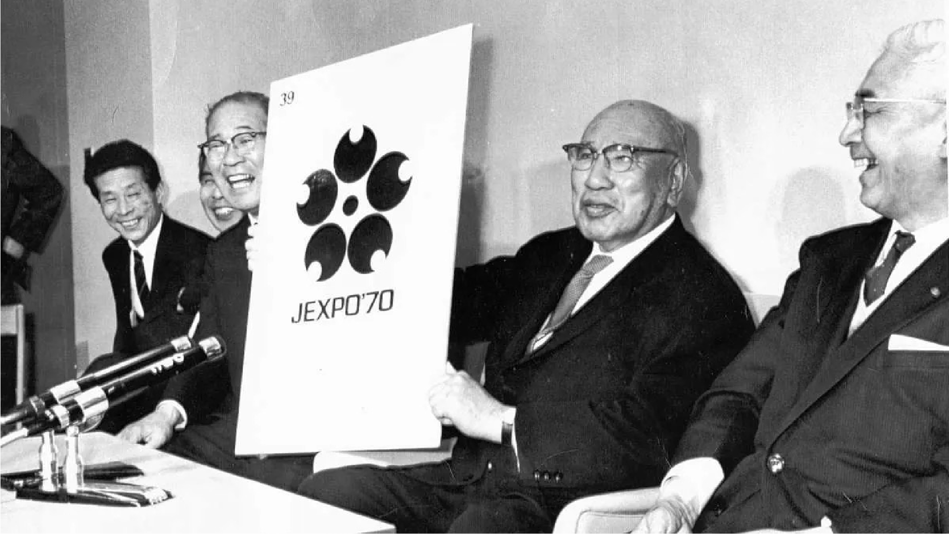 日本萬國博覽會協會會長石坂泰三於記者會上興奮展示 1970 年萬博最終標誌作品,象徵體制主導的設計時代。(圖片來源:產經新聞 WEST)